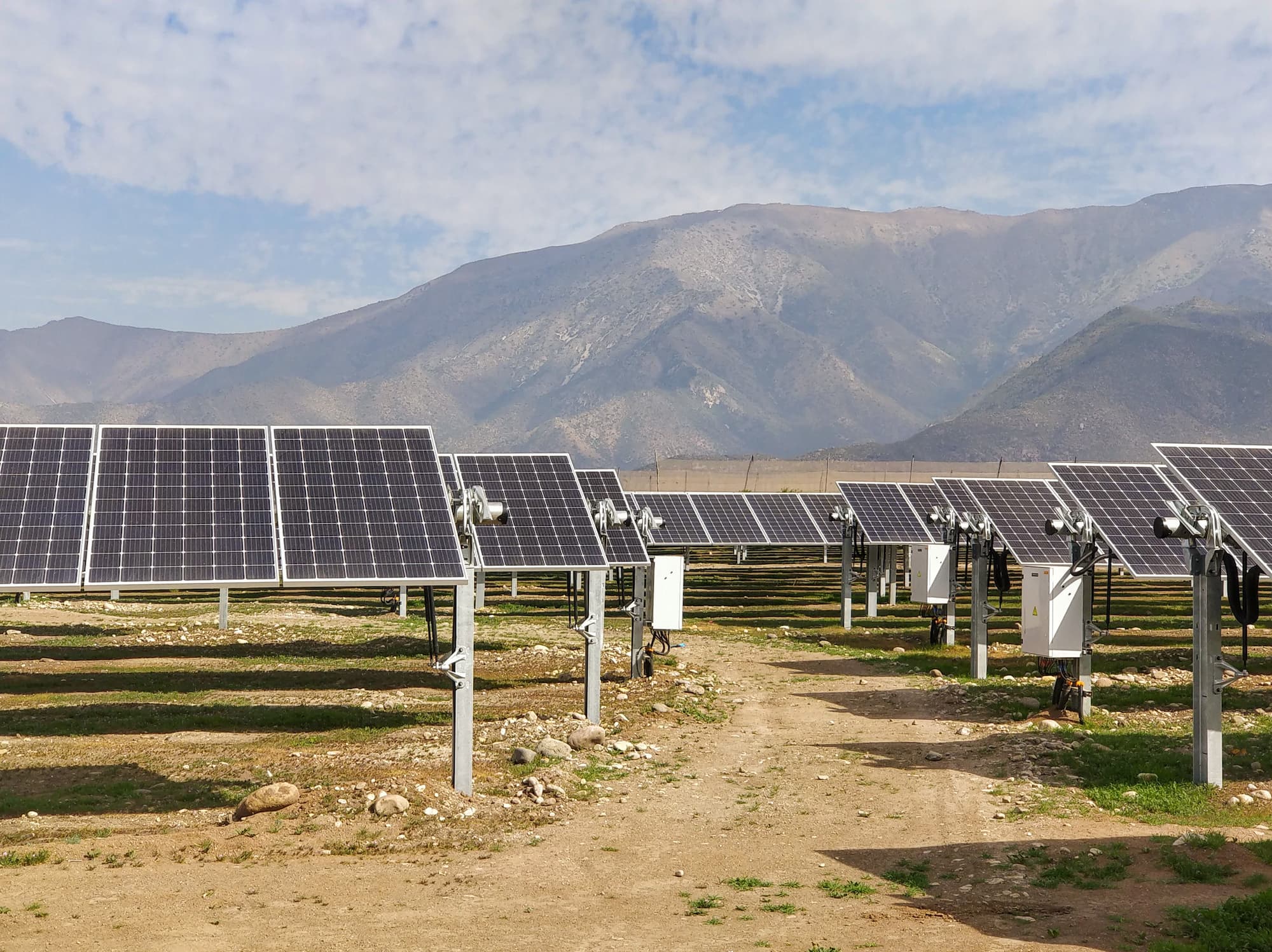 Ground-mounted solar array on a gravel site below arid mountains